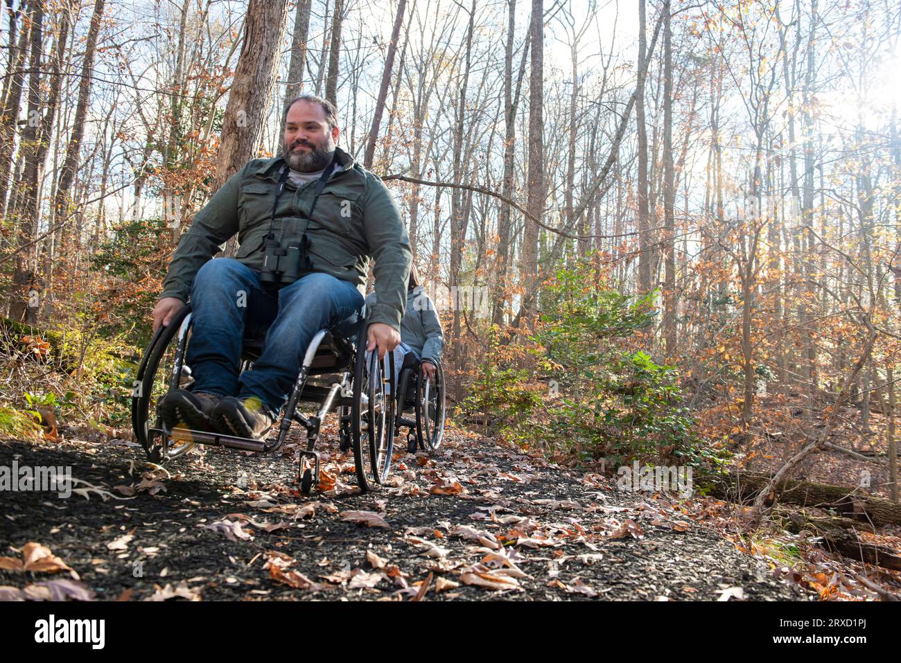 Two people use wheelchairs to hike on a crisp Autumn morning. Stock Photo