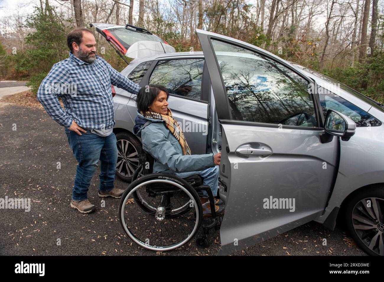 An outdoorsy couplearrives at a handicapped accessible campsite. The woman is moving from the car to her wheelchair. Both are disabled but love the ou Stock Photo