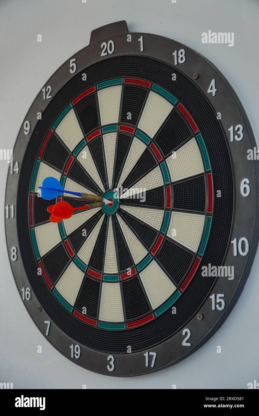 Dart board on white wall background. The dart hit the center of the