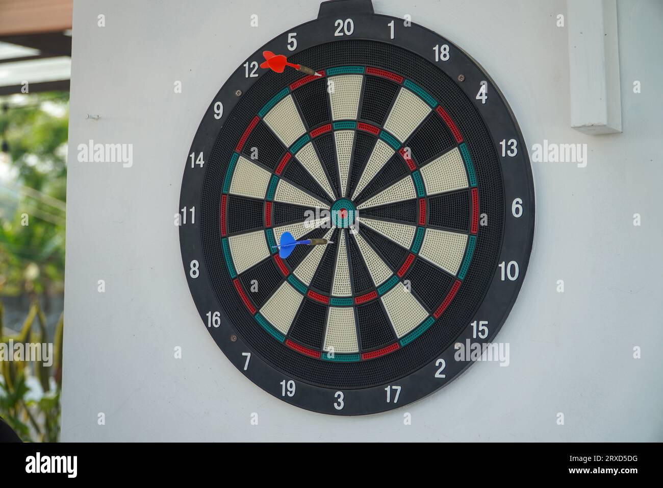 Dart board on white wall background. The dart hit the center of the
