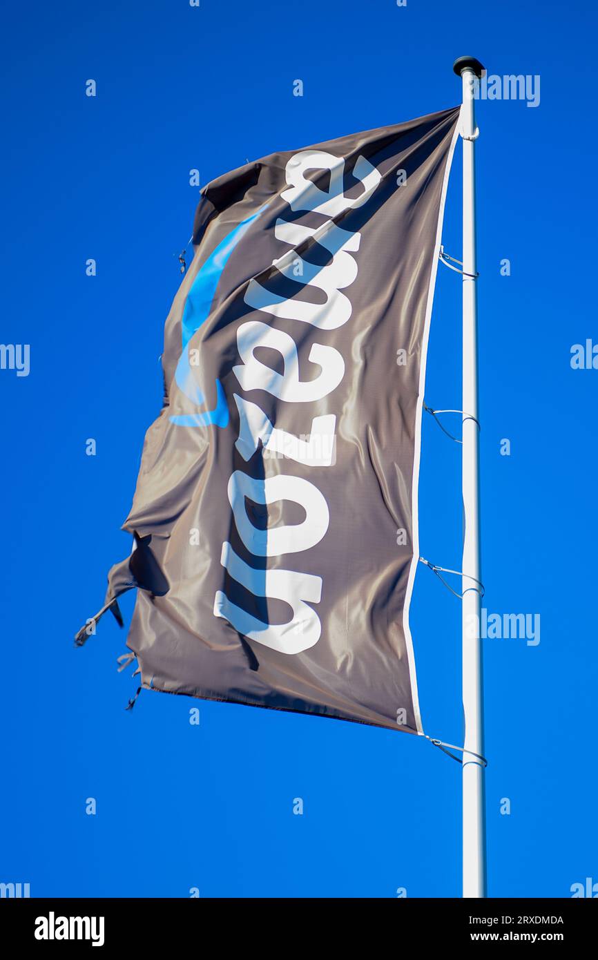 PRODUCTION - 07 September 2023, Saxony-Anhalt, Sülzetal: 'Amazon' on a waving flag in front of the Amazon logistics center in Sülzetal. Amazon is specifically recruiting members of the German armed forces. For some time now, the mail order company has been explicitly advertising its 'Military Recruitment Program' to attract military personnel as employees. In times of a shortage of skilled workers, this is a field that is apparently becoming increasingly interesting for other companies as well. Photo: Klaus-Dietmar Gabbert/dpa Stock Photo