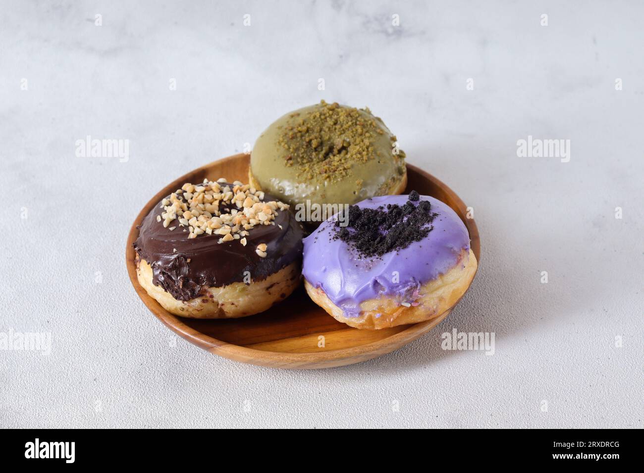 Delicious sweet donuts with different flavors served on wooden plate ...