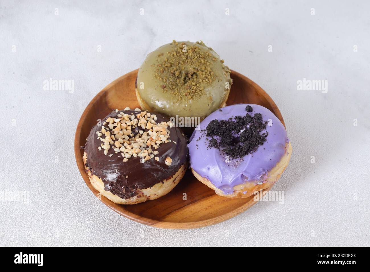 Delicious sweet donuts with different flavors served on wooden plate ...