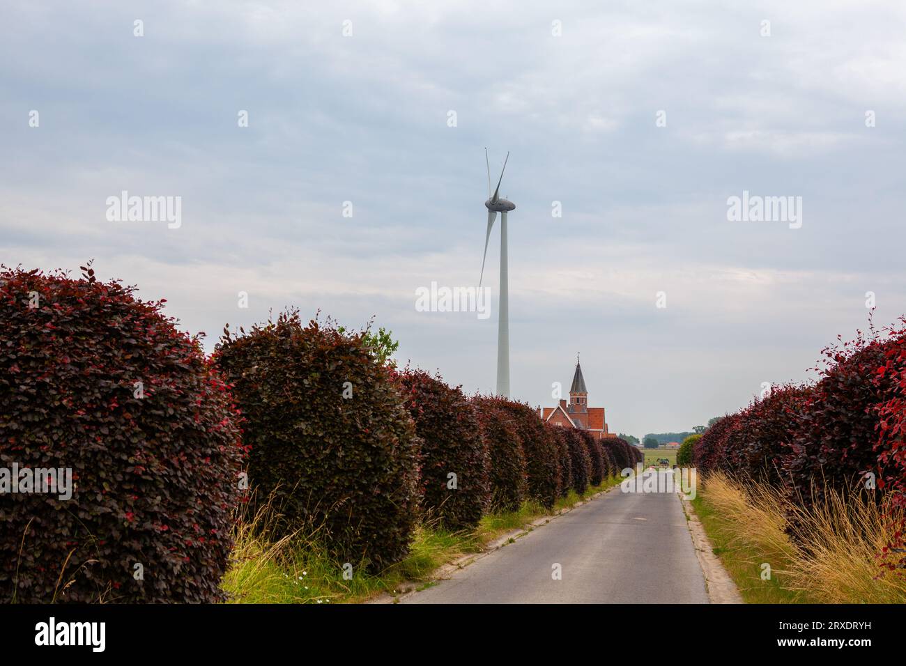 On the end of the road, there is a Windmill on a cloudy day Stock Photo