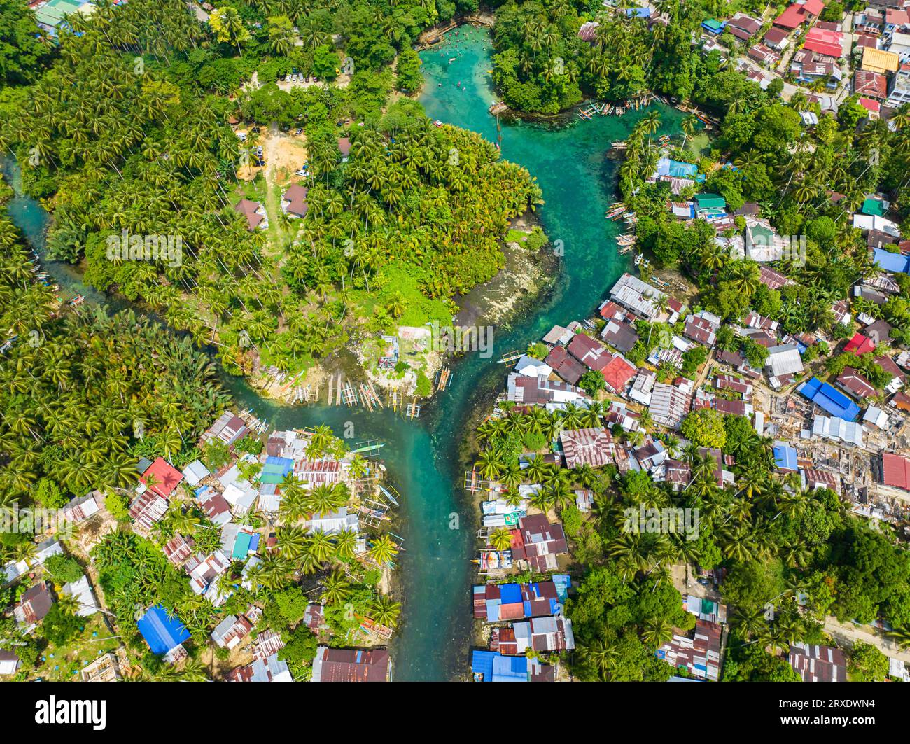 Blue clear water over the Bogac Cold Spring surrounded by villlages and tropical forest. Surigao del Sur, Philippines. Stock Photo