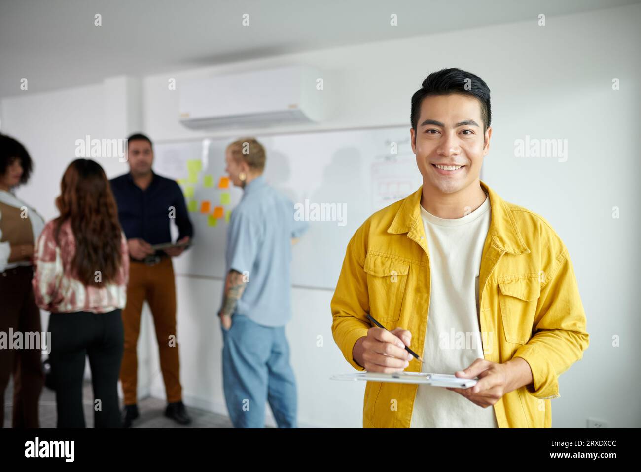 Portrait of smiling startupper taking notes in document on clipboard Stock Photo