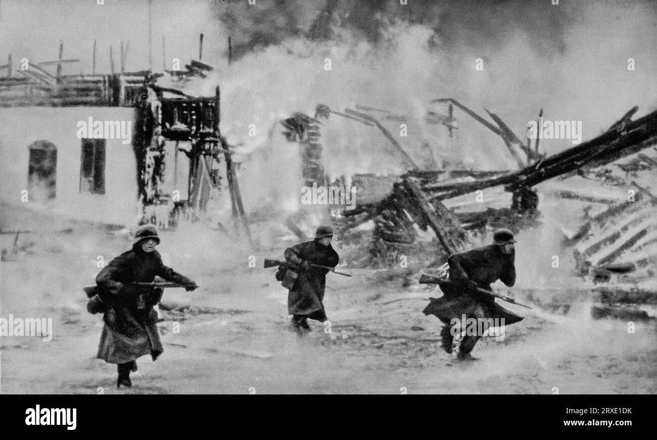 German soldiers advancing through a burning French town, during their advance  into the north of the country around the 14th May during the  Second World War. Stock Photo