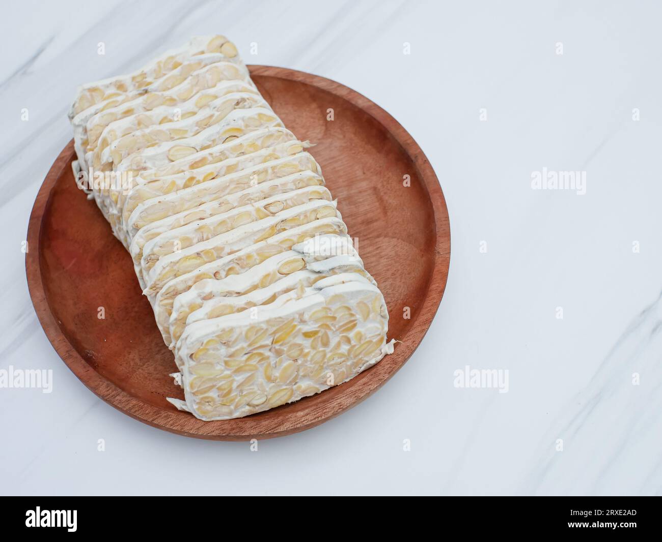 raw tempeh or tempeh. tempeh slices on wooden plate. Tempeh is made