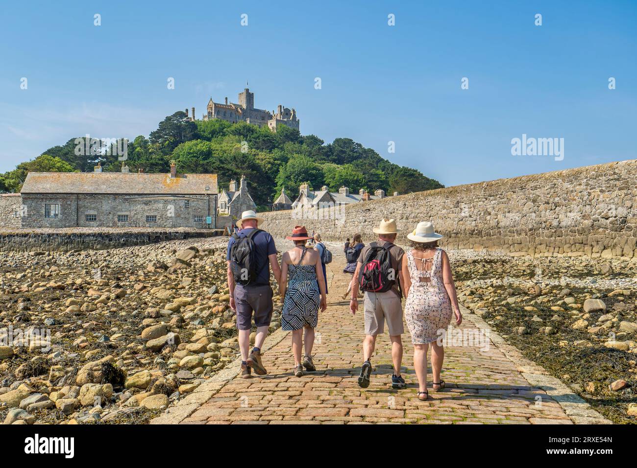 14 June 2023: Marazion, Cornwall, UK - Couples walking hand in hand on the causeway to St Michael's Mount, on a beautiful summer day. Stock Photo