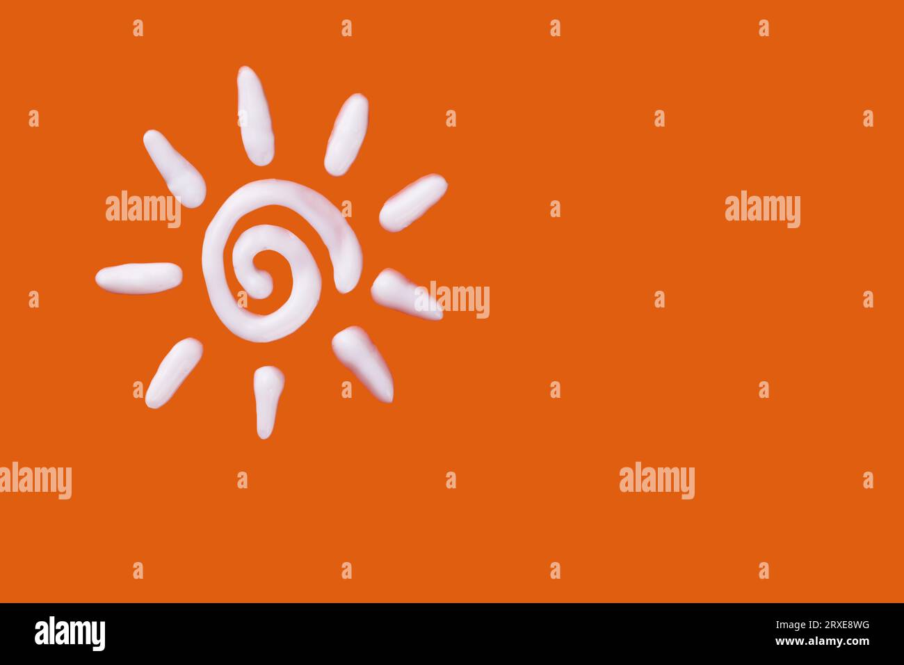 Sunscreen cream in a sun shape on orange background. Creative idea of