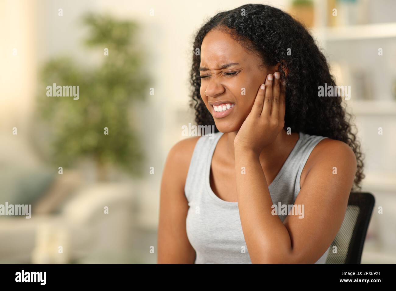 Black woman suffering otitis sitting at home Stock Photo