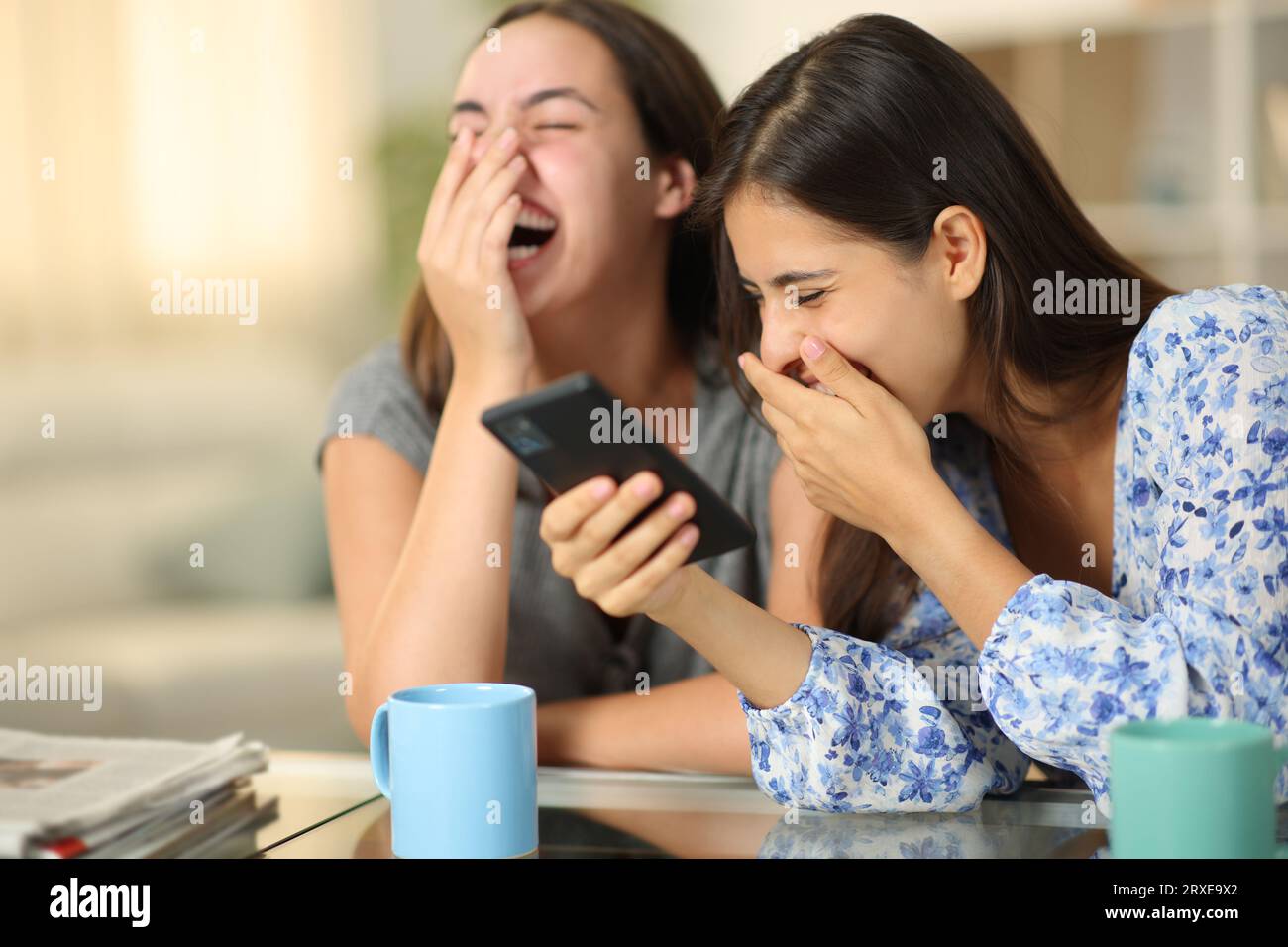 Funny friends watching media on phone laughing loud at home Stock Photo