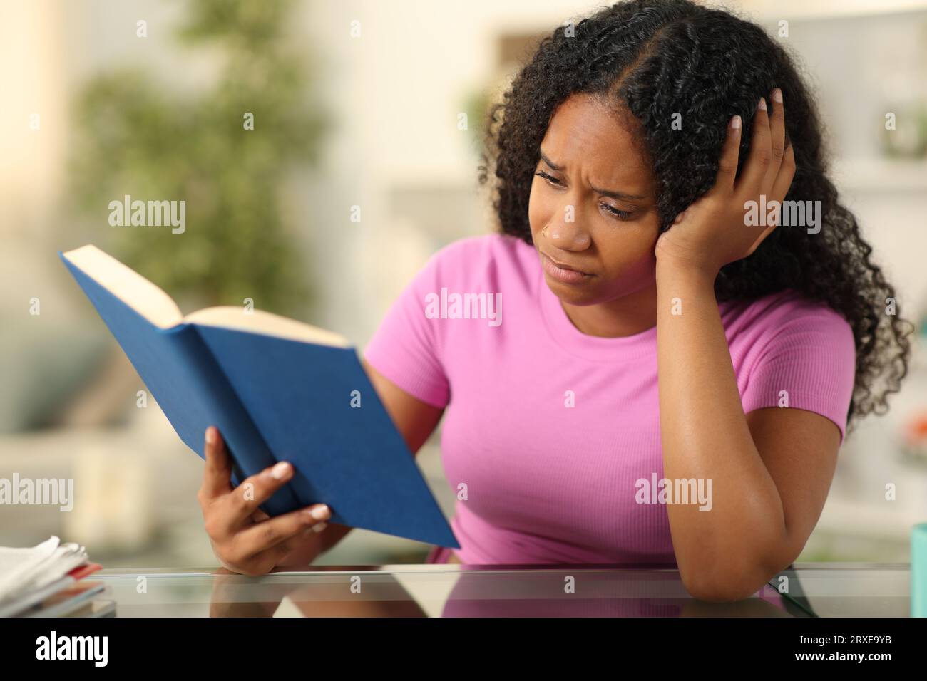 Sad book reader reading best seller sitting at home Stock Photo