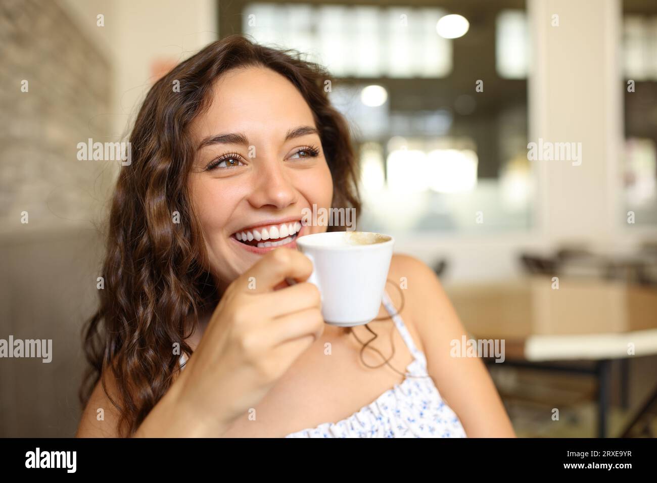 Happy woman holding coffee cup and laughing sitting in a bar Stock Photo
