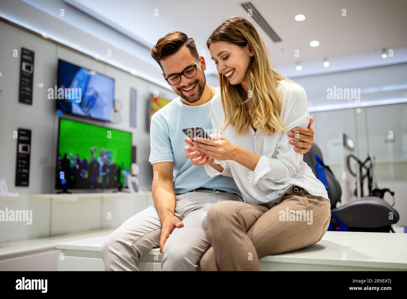 Smiling young couple looking at smartphone. Multiethnic people sharing social media on cell phone. Stock Photo