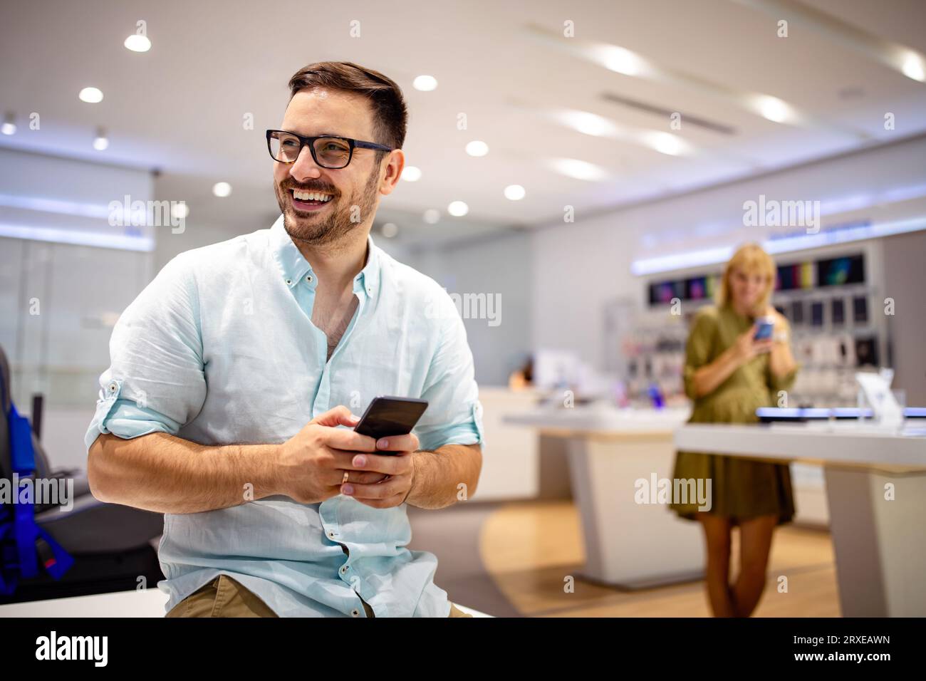 Smiling young male using mobile phone app playing game, shopping online, ordering delivery Stock Photo