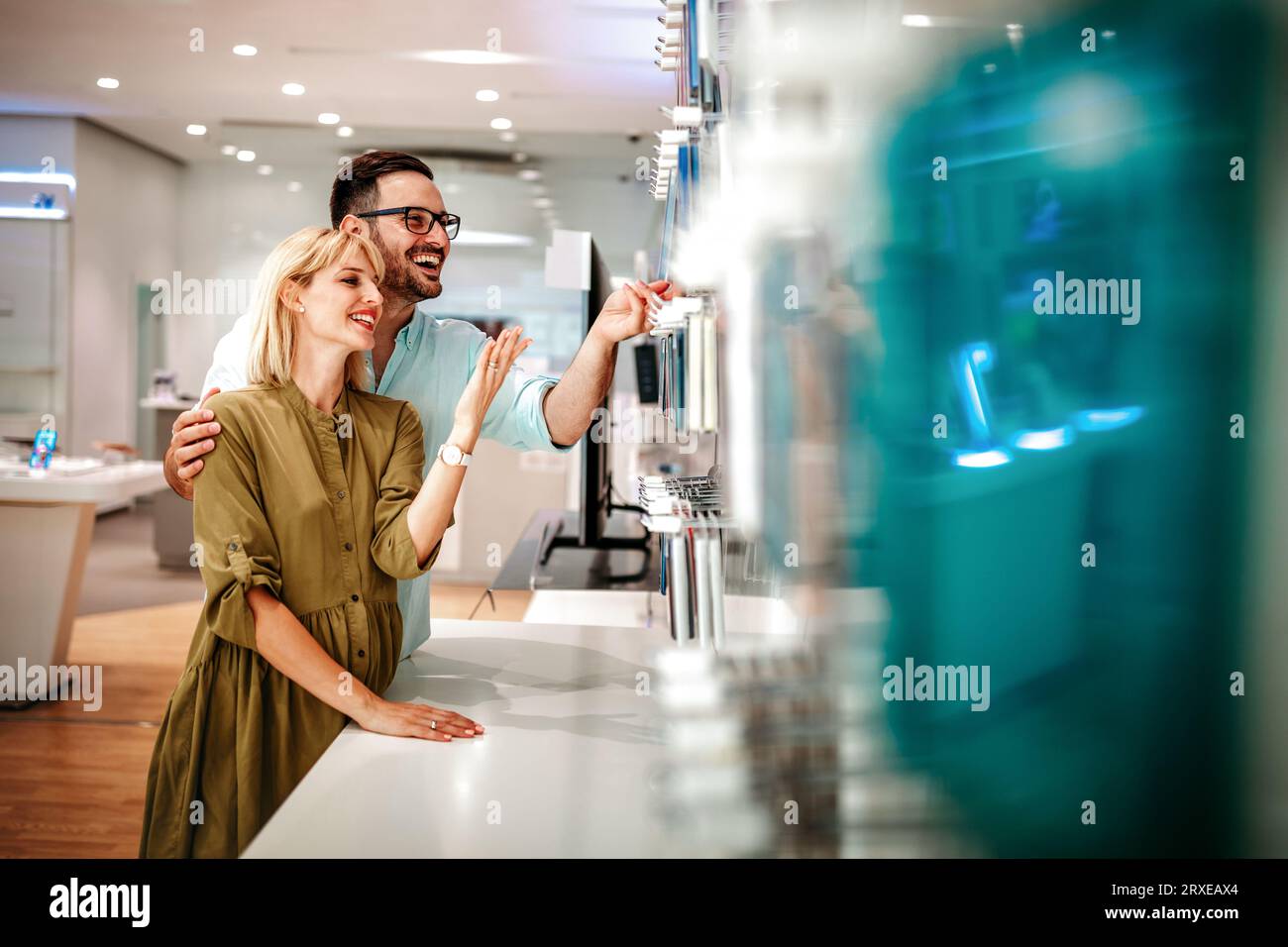 Shopping a new digital device. Happy couple buying a smartphone in store. Stock Photo