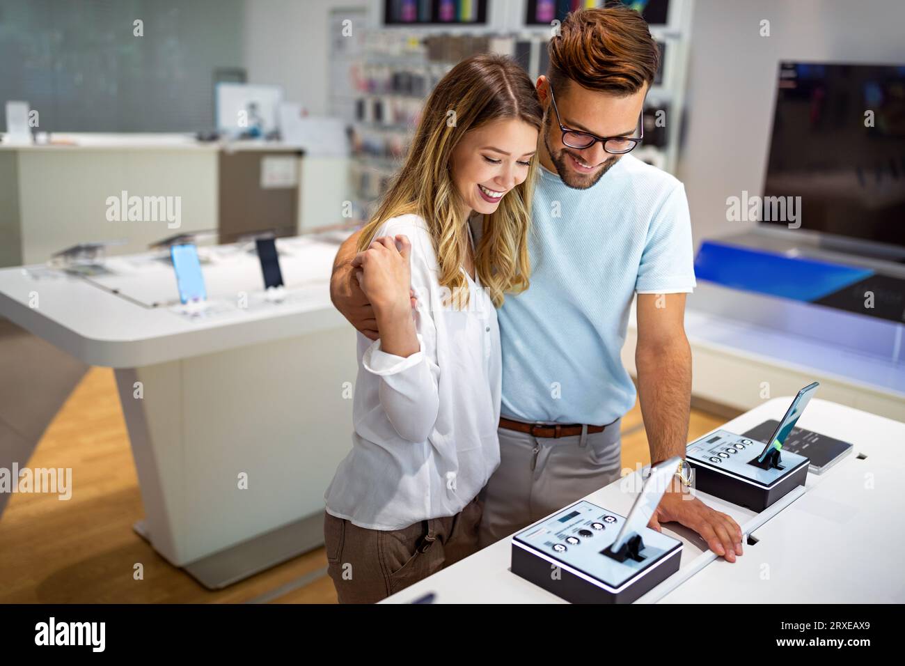 Tech shopping device gadget concept. Happy young people buying a new smartphone in mobile shop. Stock Photo