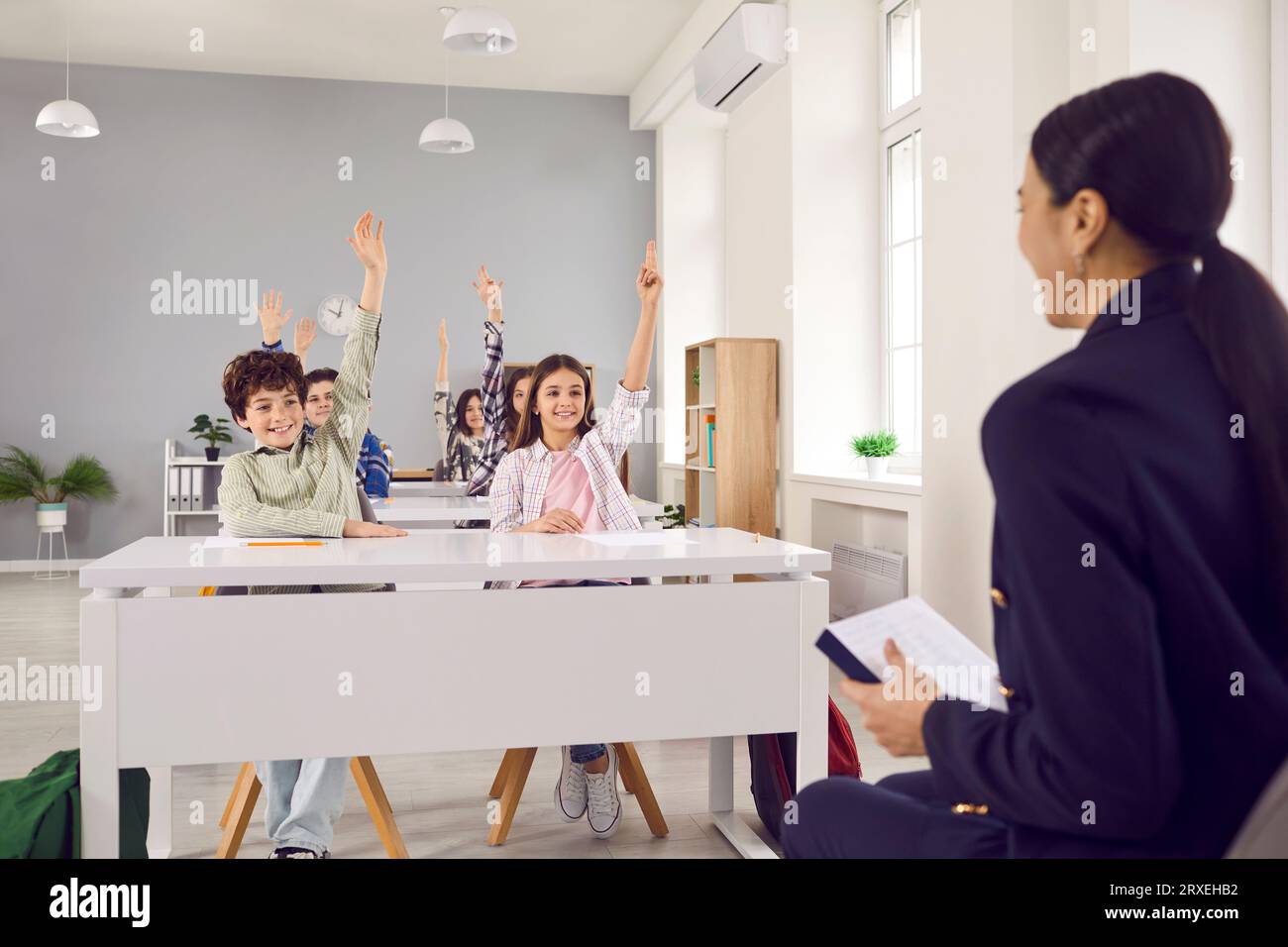 Cute smiling pupils raising their hands during class at elementary ...