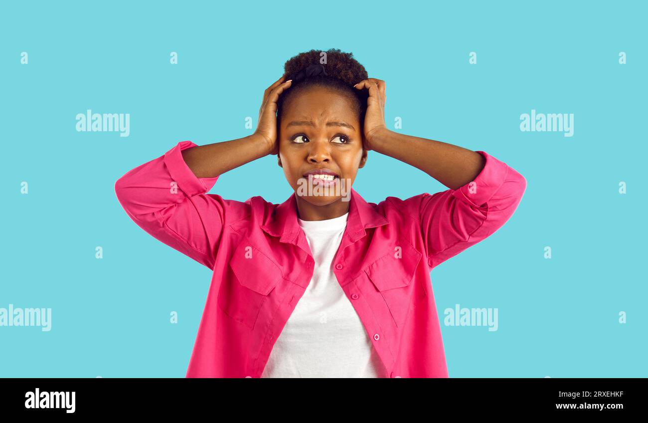 Funny woman who made mistake or forgot something grabs her head on light blue background. Stock Photo