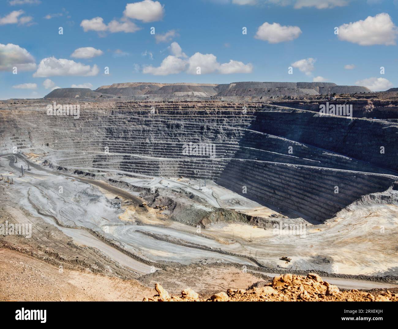 diamond mine open pit, panoramic view of the quarry layers, earth moving machines in the background Stock Photo