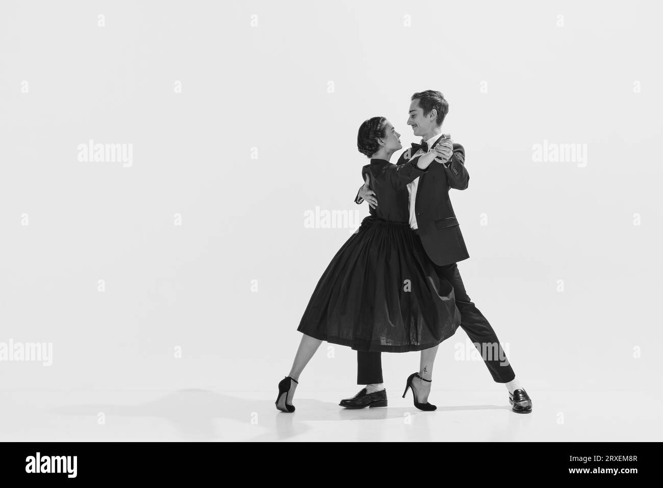 Black and white. Passion and love. Beautiful young woman and man in stylish clothes dancing on white background Stock Photo