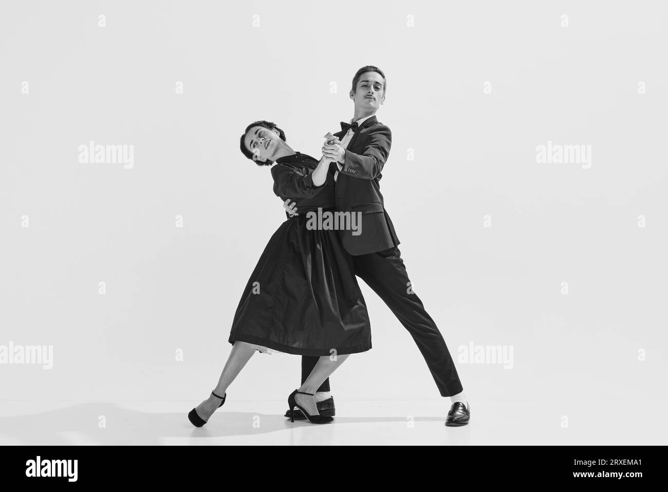 Black and white. Passion and love. Beautiful young woman and man in stylish clothes dancing on white background Stock Photo