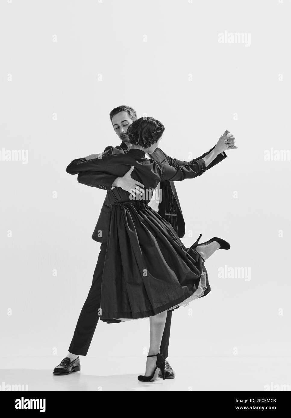 Rhythm and freedom. Black and white. Beautiful young woman in elegant black dress dancing with stylish and handsome man Stock Photo