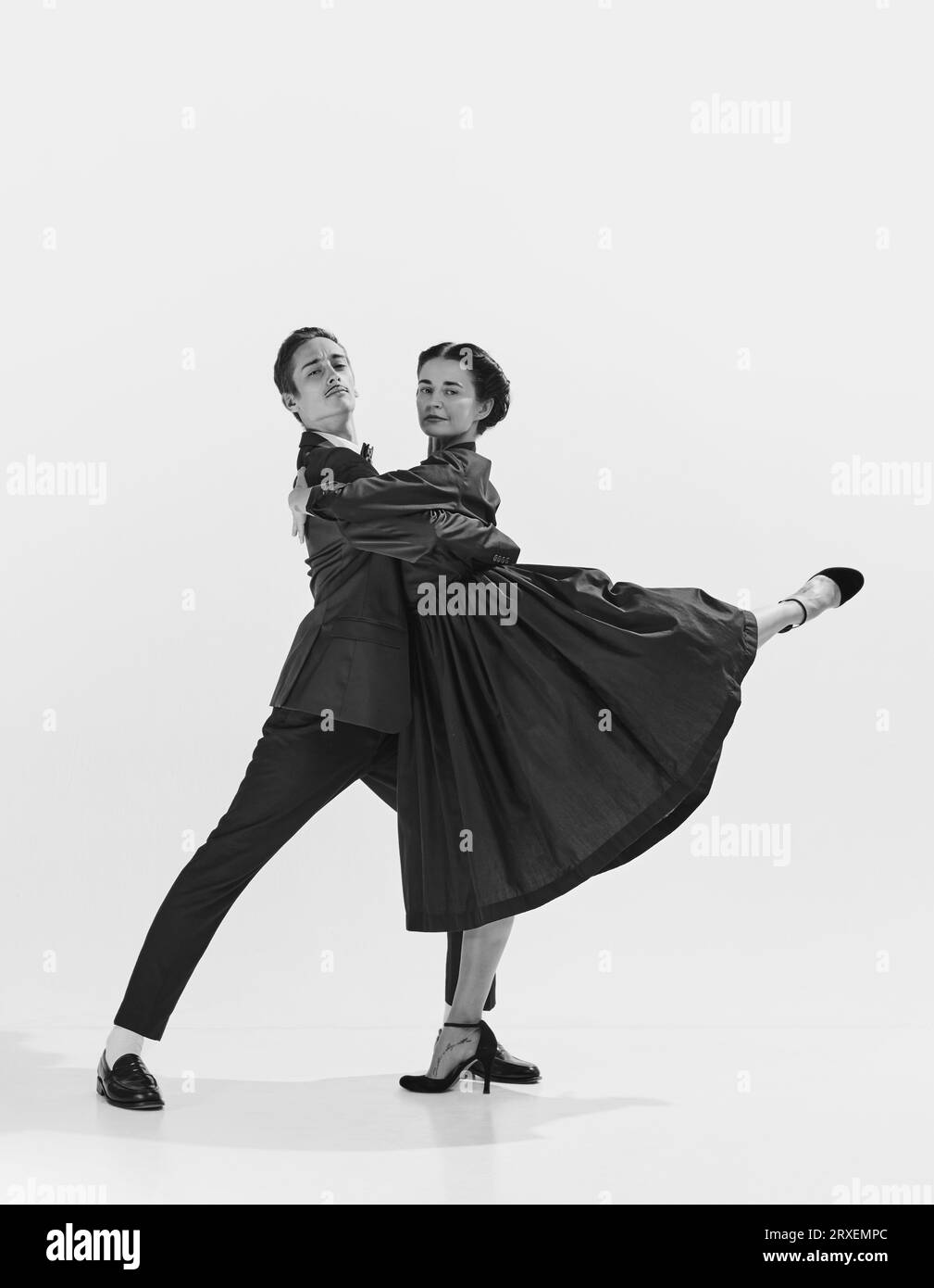 Talented and artistic young man in suit and beautiful woman in elegant dress dancing lindy hop. Black and white. Stock Photo