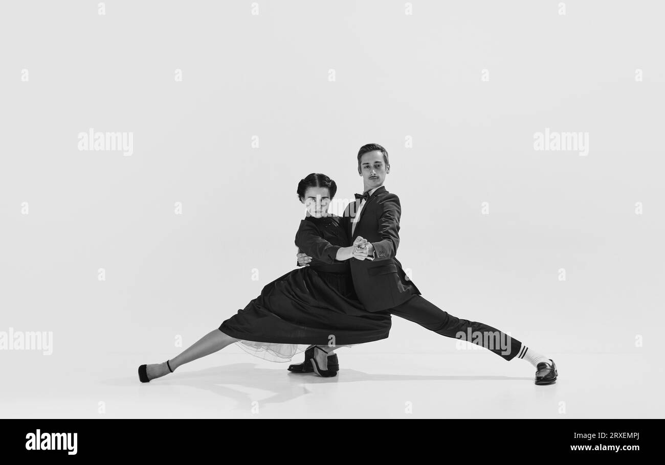 Talented and artistic young man in suit and beautiful woman in elegant dress dancing lindy hop. Black and white. Stock Photo