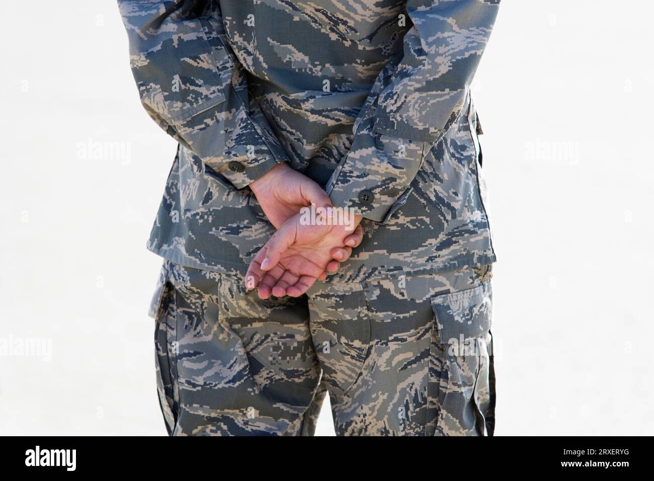 Close up, rear view midsection of person in a military uniform with their hands clasped behind their back. Stock Photo