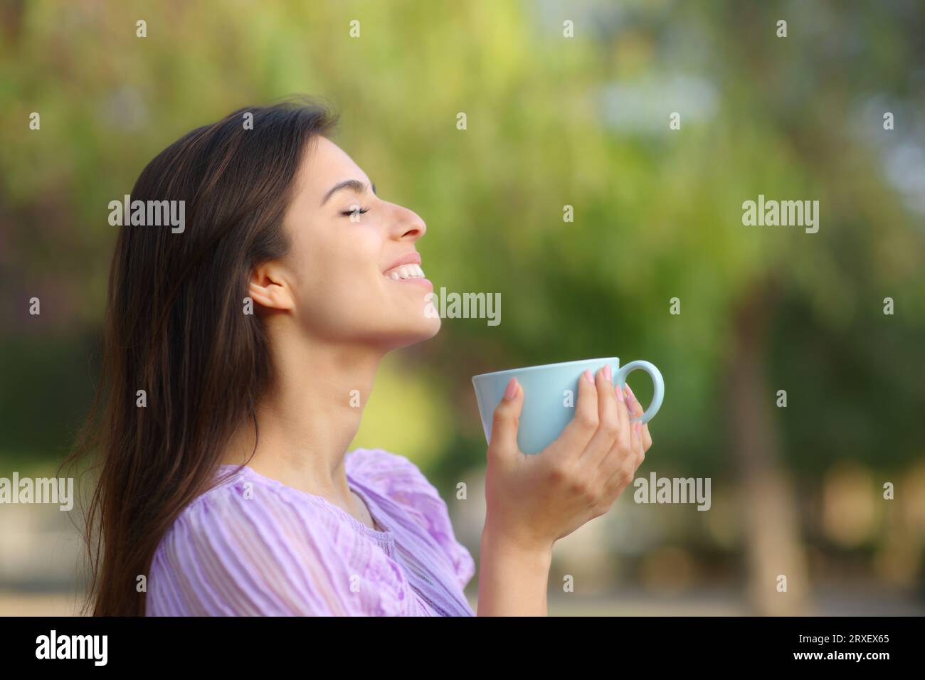 Profile of a happy woman drinking and breathing in a park Stock Photo