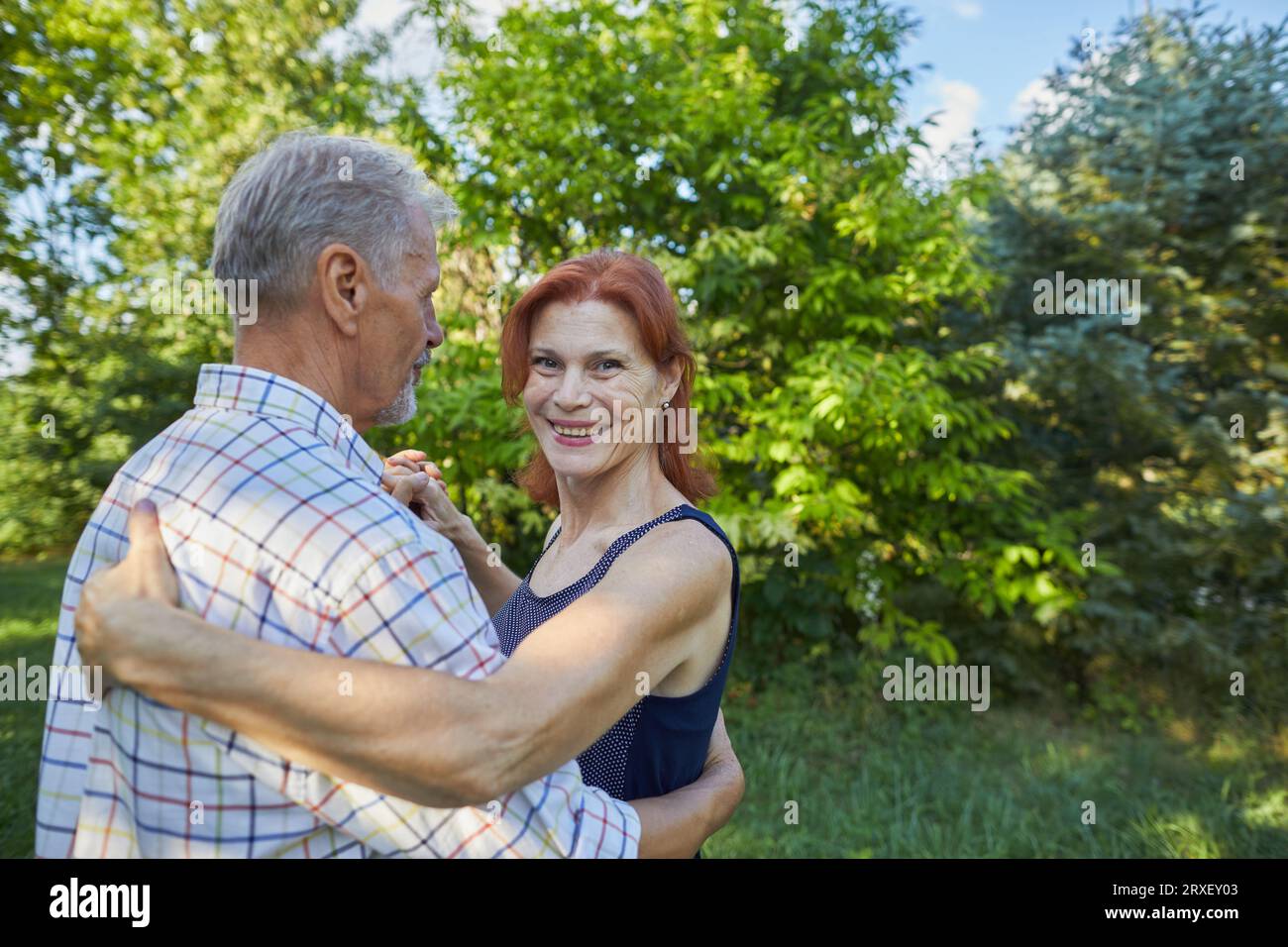 Smiling adult woman on outdoor dances with man and look at camera Stock Photo