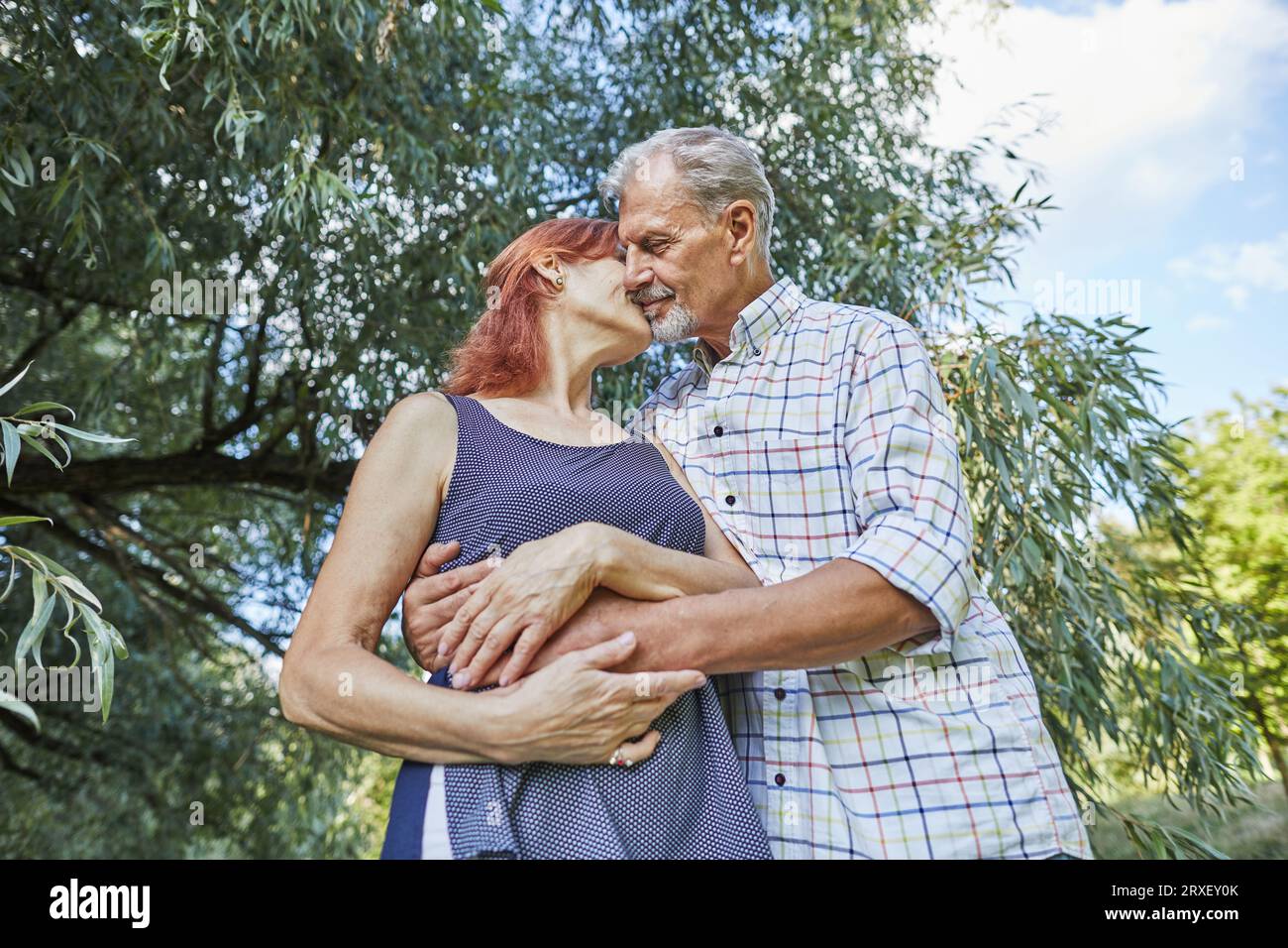 senior man gently hugs and kisses woman Stock Photo