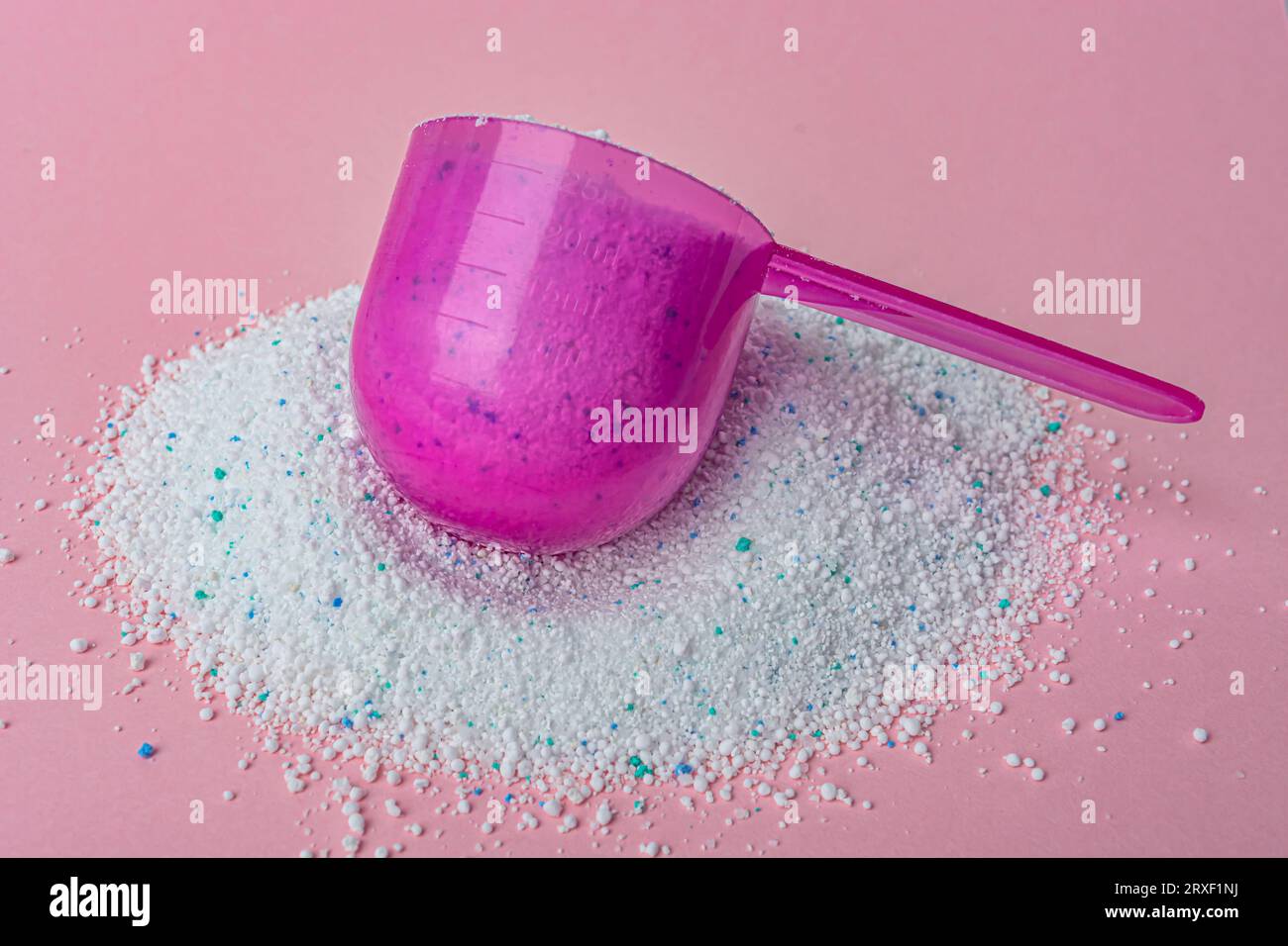 Washing powder in plastic spoon on pink background top view. High quality photo Stock Photo