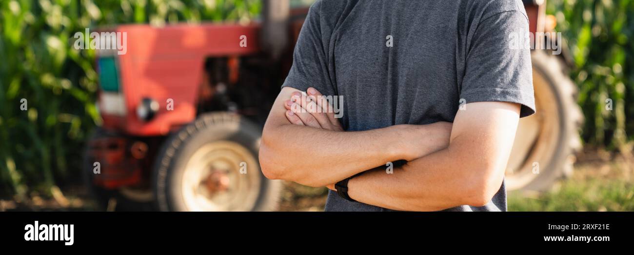 A farmer stands in front of a agricultural tractor Stock Photo - Alamy