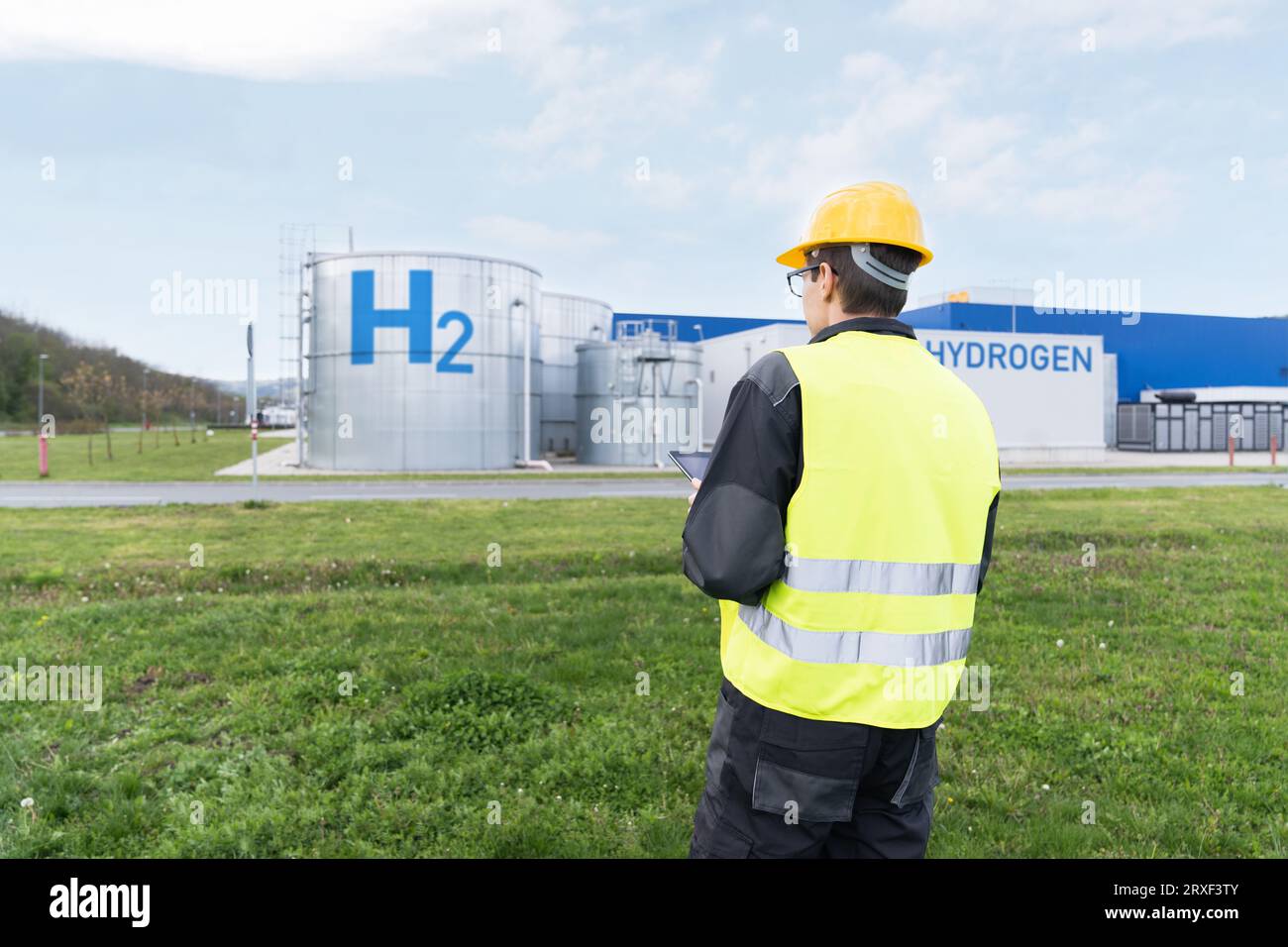 Engineer with tablet computer on a background of Hydrogen factory.. Stock Photo