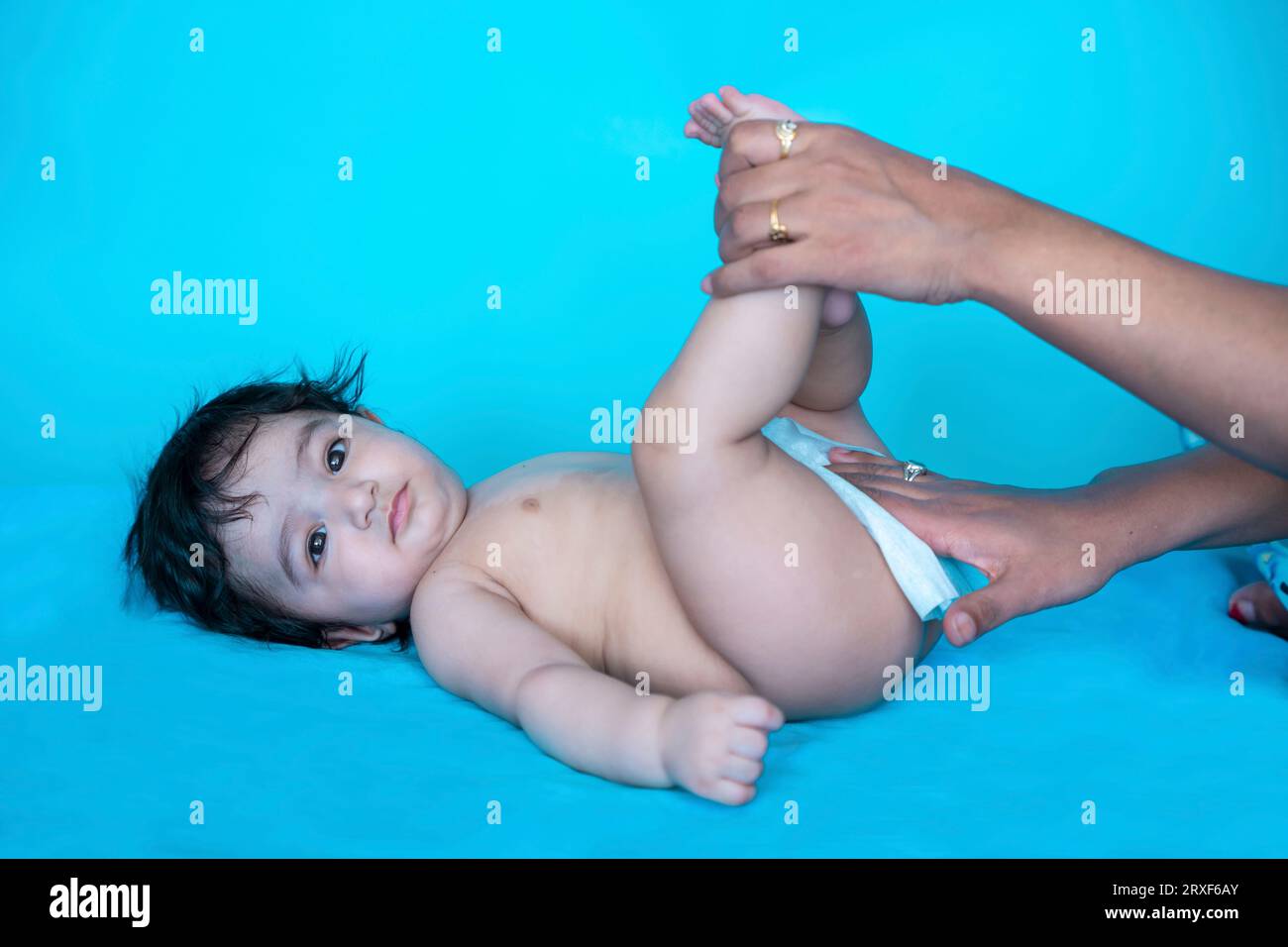 Indian mother cleaning up and wipes body and legs of baby by wet tissue. newborn baby. Top view. Stock Photo