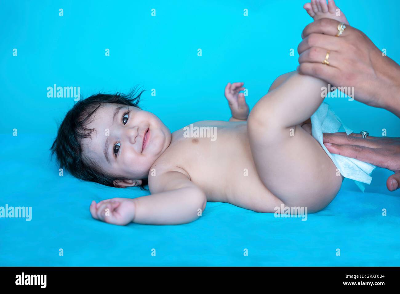 Indian mother cleaning up and wipes body and legs of baby by wet tissue. newborn baby. Stock Photo