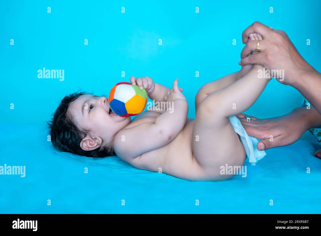 Indian mother cleaning up and wipes body and legs of baby by wet tissue. newborn baby. Stock Photo