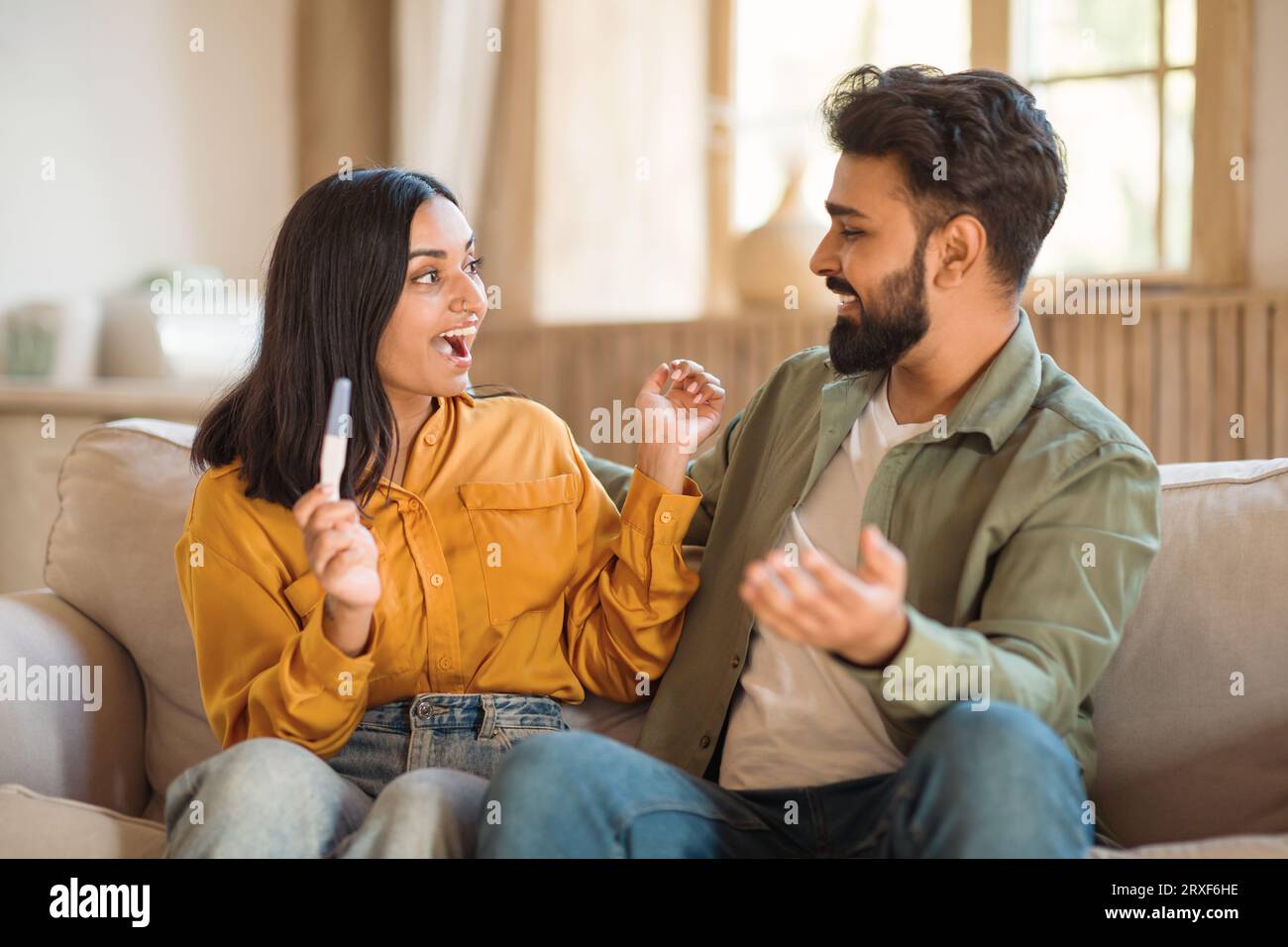 Happy young indian couple rejoicing positive pregnancy test, sitting on ...