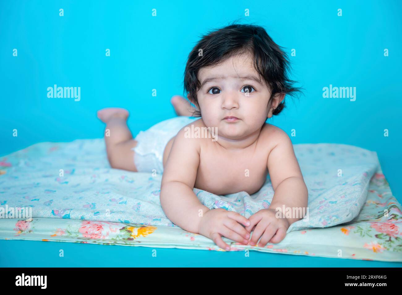 Small six months old cute indian baby boy wearing diaper lying on floor