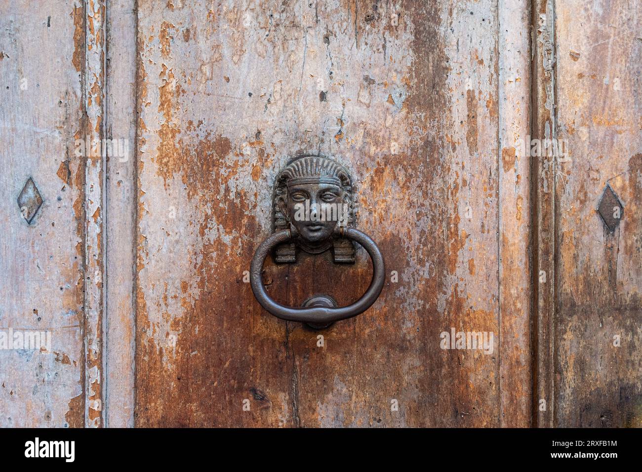 Close-up of an old wooden door with an iron knocker in the shape of the head of an Egyptian pharaoh, Italy Stock Photo