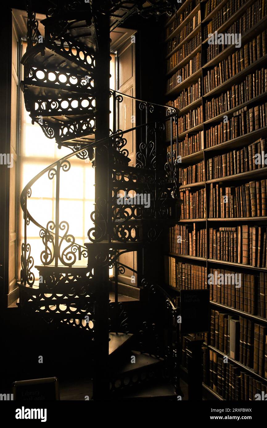 A spiral staircase near a bookshelf inside the Old library in Trinity College, Dublin Ireland