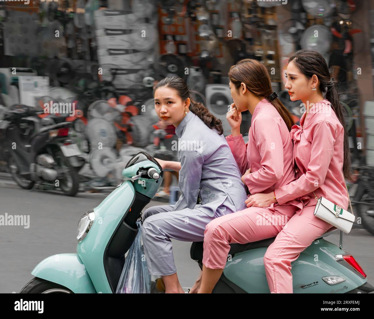 Three pretty young Vietnamese women riding on Vespa style moped, Hanoi, Vietnam, Asia Stock Photo