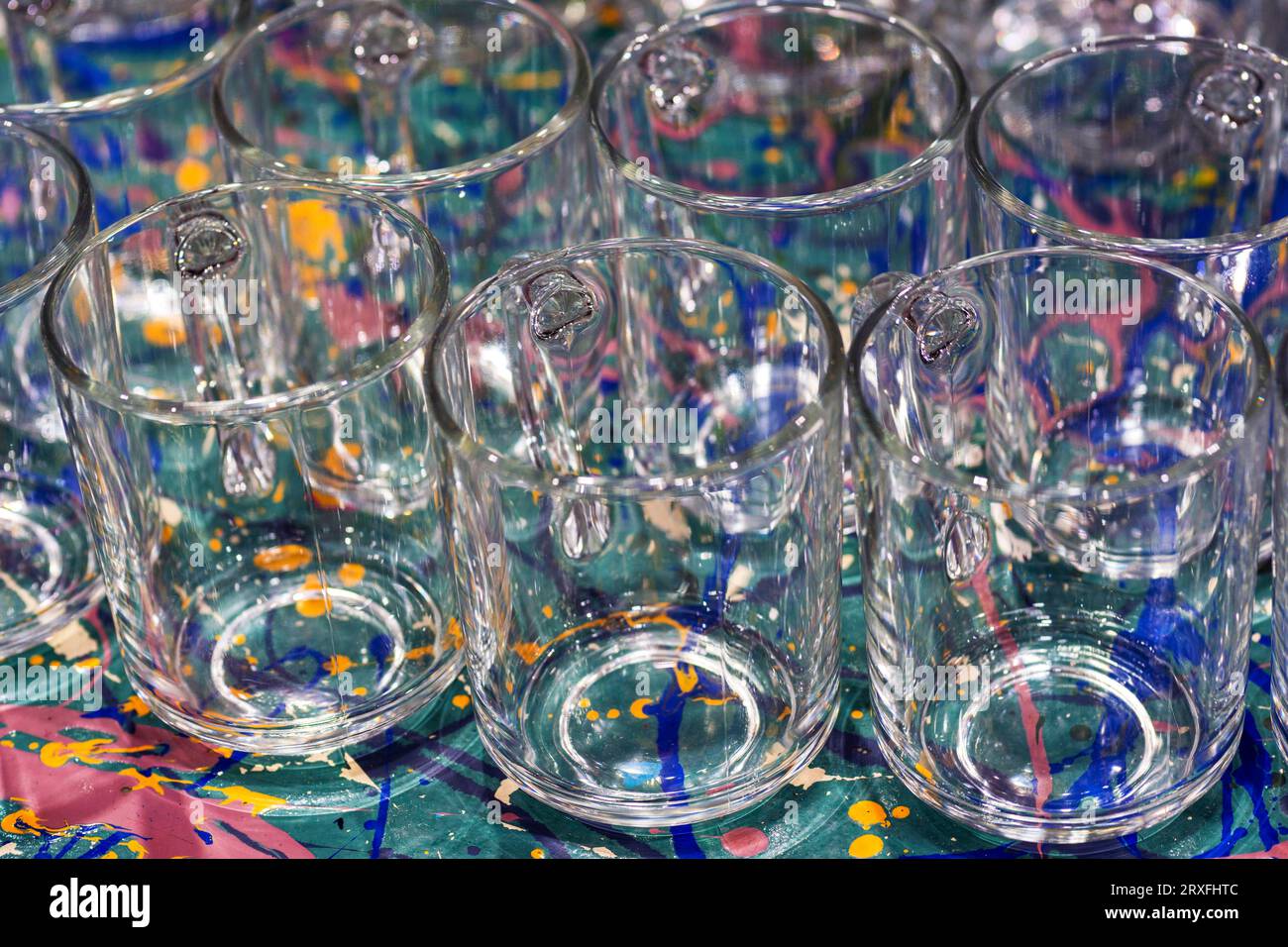 Transparent cups on a color table. It is a lot of glass cups. Empty