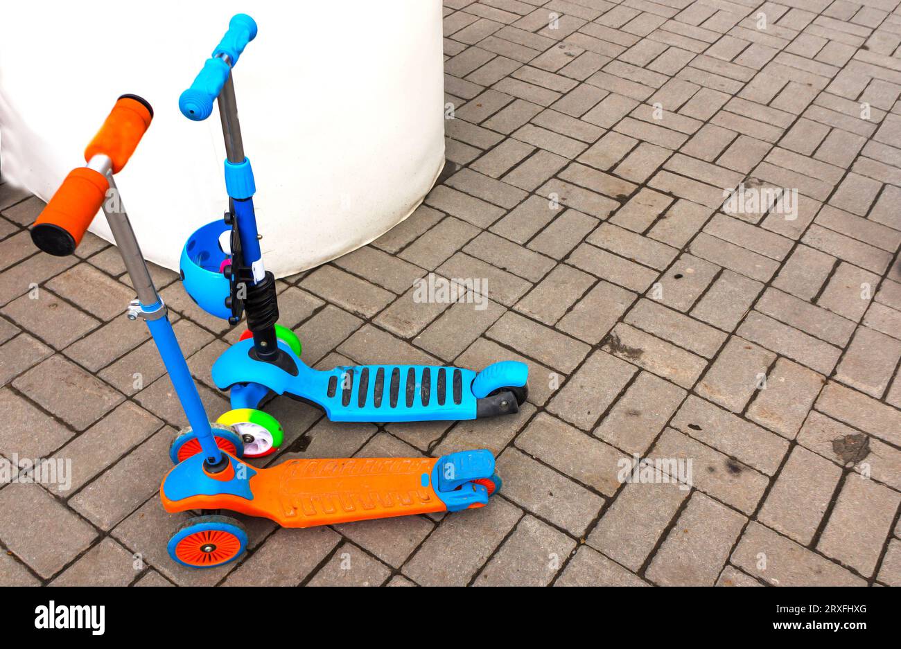 Children's scooters of different colors.The concept the childhood, walking transport for children. Stock Photo