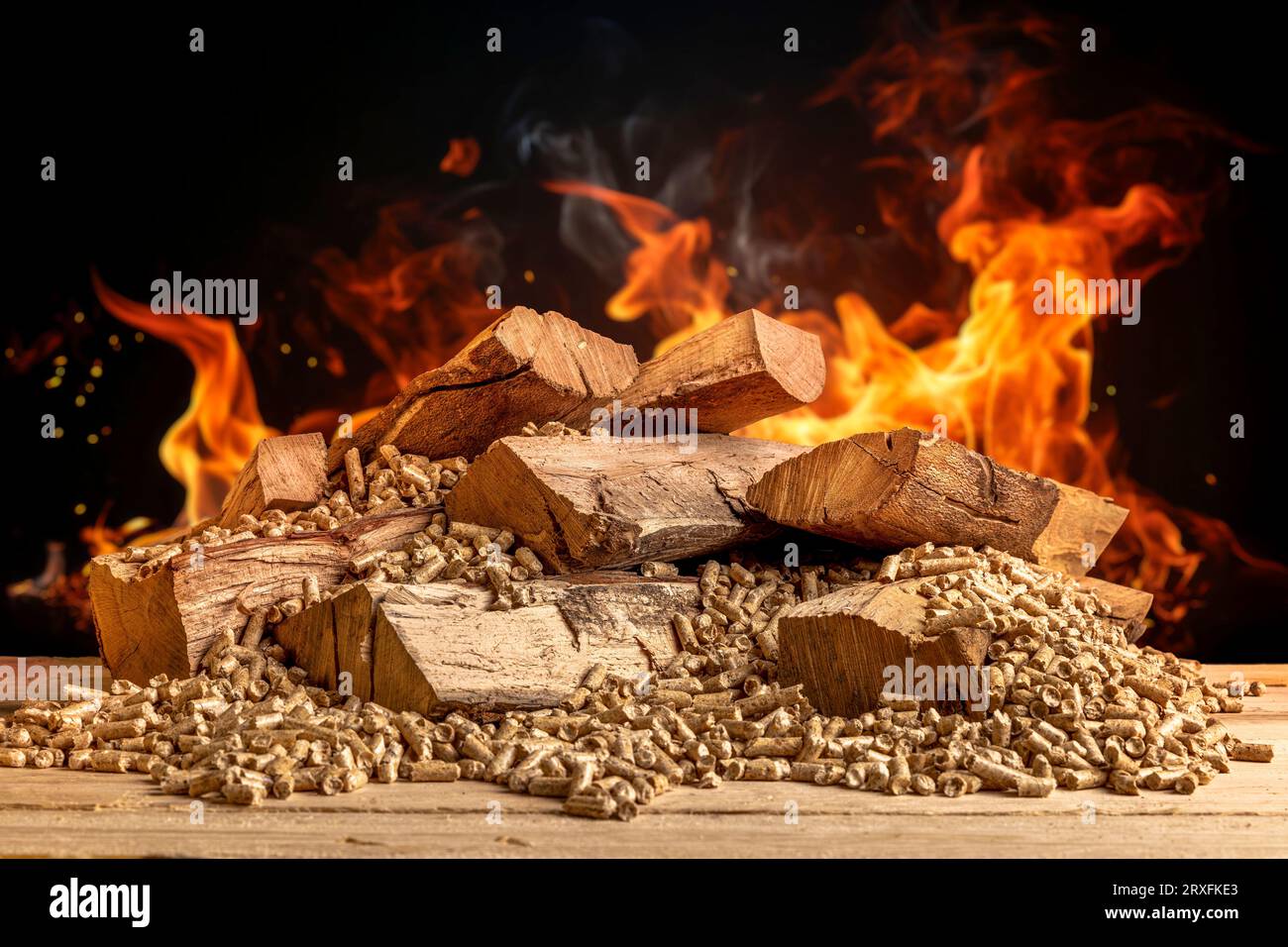 wood pellets and logs with flames in the background Stock Photo