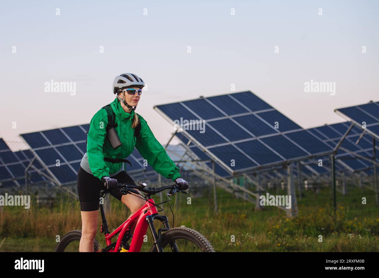 https://c8.alamy.com/comp/2RXFM0B/portrait-of-a-beautiful-cyclist-riding-in-front-of-solar-panels-at-a-solar-farm-2RXFM0B.jpg