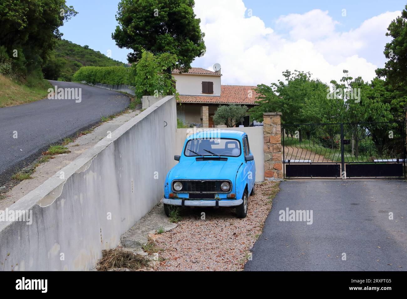 an old-timer economy car stands parked on a roadside in Corsica Stock Photo